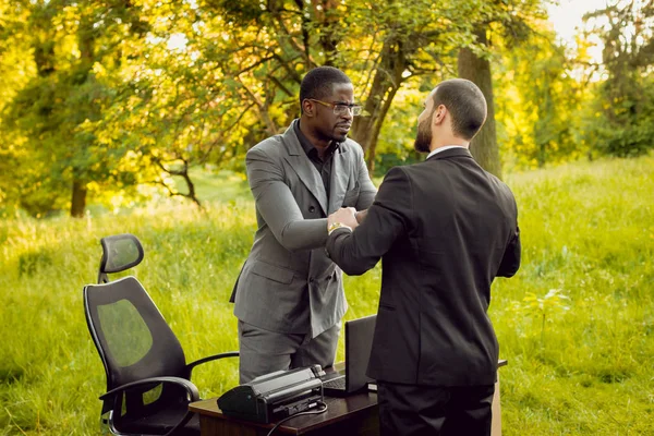 Parkta iş adlı iki genç çok kültürlü businessmans. Uzak iş kavramı.