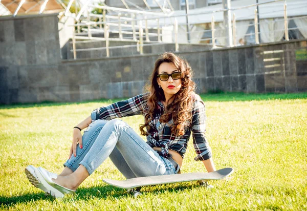 Genç esmer kız açık havada kaykay ile poz