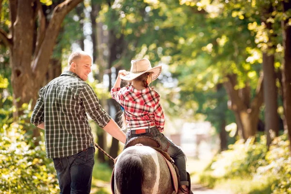 Kovboy şapkası binme midilli küçük kız babasıyla Park