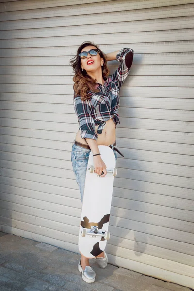 Genç esmer kız açık havada kaykay ile poz