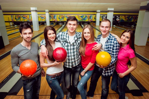 Cheerful friends at the bowling alley with balls