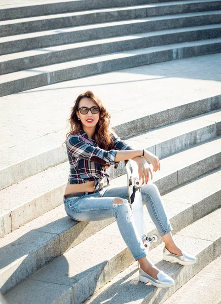 Genç esmer kız açık havada kaykay ile poz