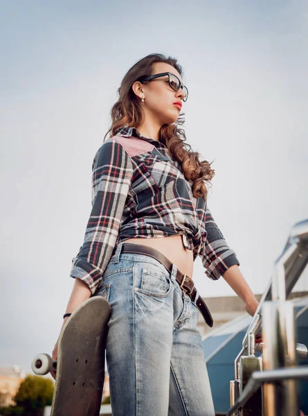 Genç esmer kız açık havada kaykay ile poz