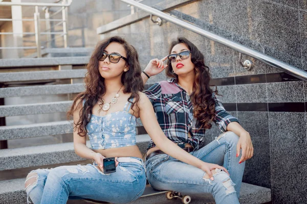 İki genç karışık yarış kız rahat kıyafetler ile kaykay sokakları etrafında yürüyüş içinde