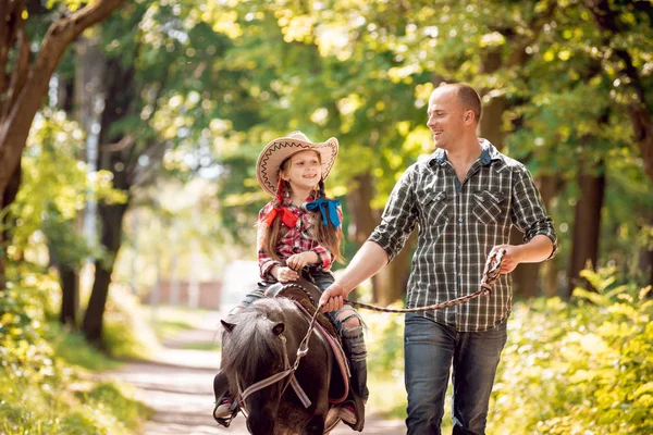 Kovboy şapkası binme midilli küçük kız babasıyla Park