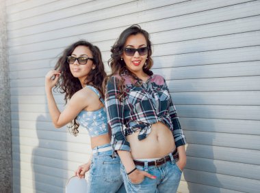 İki genç karışık yarış kız rahat kıyafetler ile kaykay sokakları etrafında yürüyüş içinde