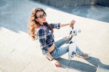 Genç esmer kız açık havada kaykay ile poz