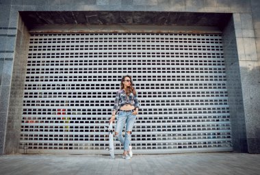 Güzel dalgalı saçlı öpebileceğinize kız açık havada kaykay ile poz Kareli gömlekli