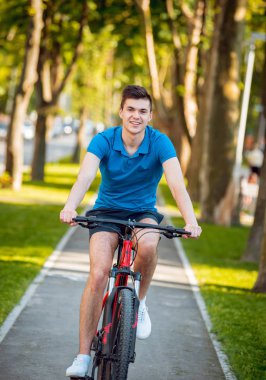 Mutlu genç beyaz adam Yeşil Bisiklet şeritli üzerinde Bisiklete binme