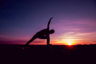 Genç kız yoga çatıda. Siluet