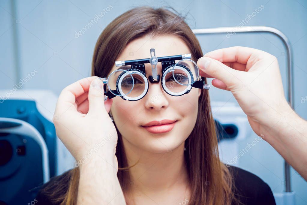 Young woman checking her vision with ophthalmologist. Medical equipment.