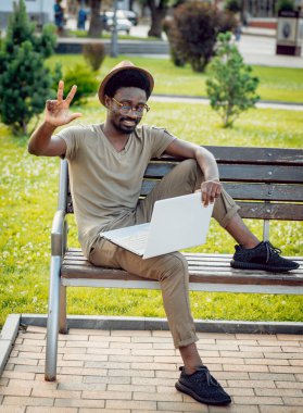 Afrika delikanlı şapka ve gözlük yeşil Şehir Parkı içinde laptop ile