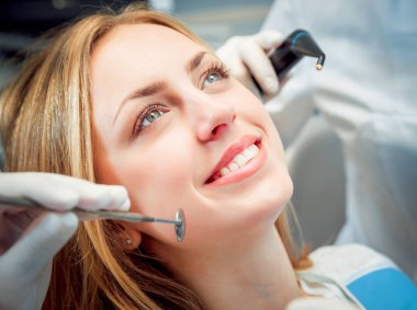 Genç kadın diş ofiste gülümsedi. Tıbbi donatımı