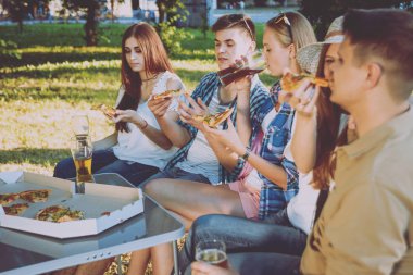 Pizza yemek Park piknik üzerinde neşeli arkadaşlar.