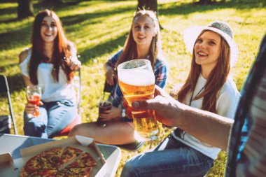 Parkta piknik neşeli Beyaz arkadaşlar. Gülümseyen ve konuşurken, enjoing pizza bira ile.