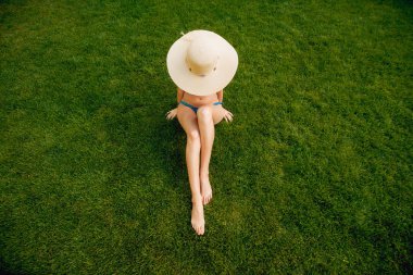 Kız bikini ve şapka yeşil çimenlerin üzerinde rahatlatıcı