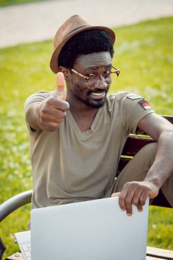 Afrika delikanlı şapka ve gözlük yeşil Şehir Parkı içinde laptop ile