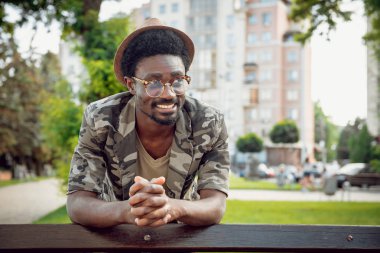 Genç Afrika adam şapka ve gözlük enjoing Parkta yürümek kadar kolay yeşil şehir