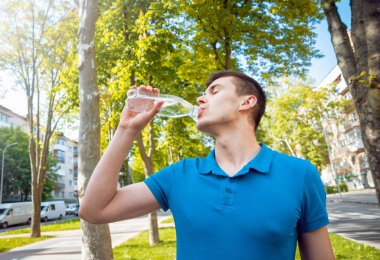 Bir şişe su olan bir adam. Parkta