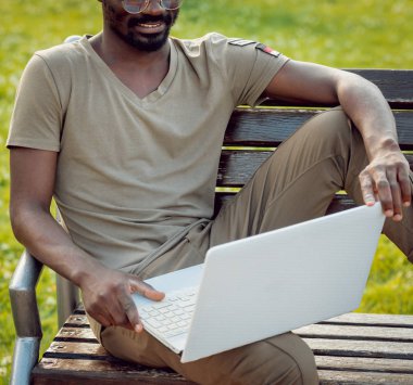 Afrika delikanlı şapka ve gözlük yeşil Şehir Parkı içinde laptop ile