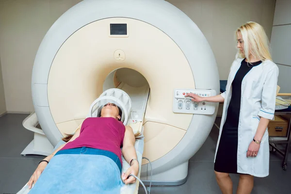 Female caucasian doctor and femele middle eastern patient in MRI room at hospital.