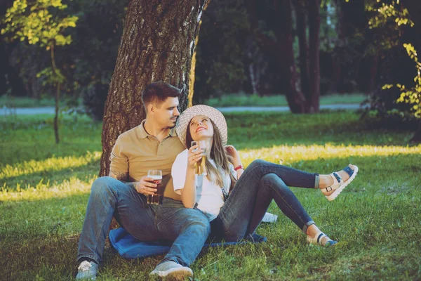 Happy couple on picnic in park eating pizza and drinking beer.