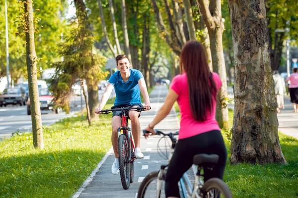Genç çift yeşil Bisiklet lane güneşli bir günde Bisiklete binme