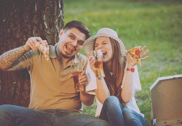 快乐情侣野餐在公园里吃比萨饼和喝啤酒 — 图库照片