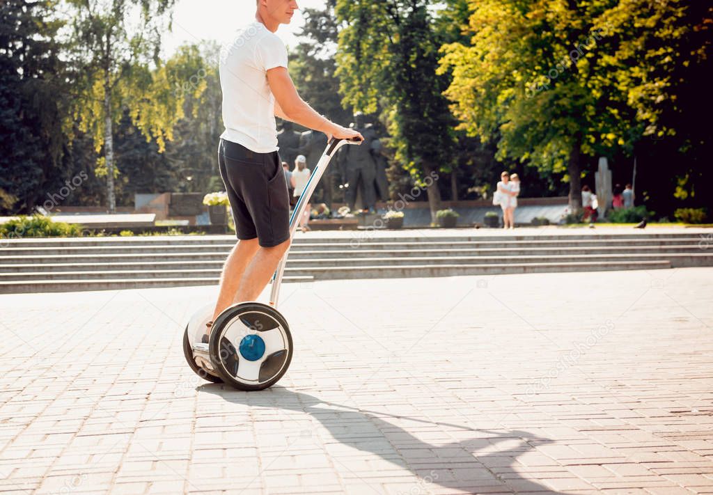 Young caucasian man riding on segway in city park