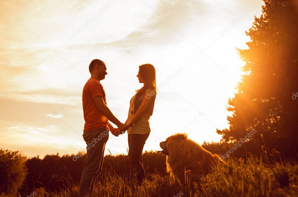 Young couple with their dog chow-chow walking in the park and having good time