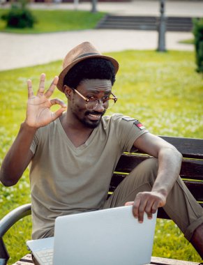Afrika delikanlı şapka ve gözlük yeşil Şehir Parkı içinde laptop ile