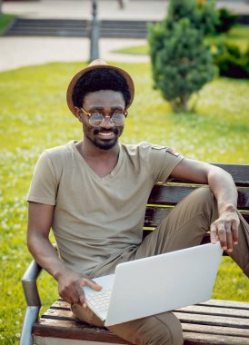 Afrika delikanlı şapka ve gözlük yeşil Şehir Parkı içinde laptop ile