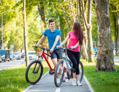 Genç çift yeşil Bisiklet lane güneşli bir günde Bisiklete binme