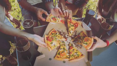 Pizza yemek Park piknik üzerinde neşeli arkadaşlar.