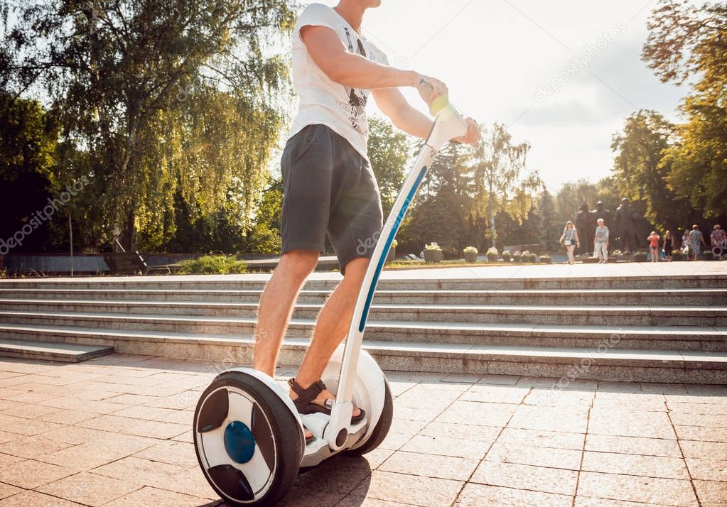 Young caucasian man riding on segway in city park