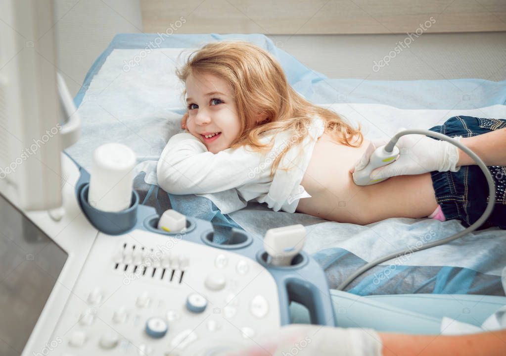 Little blonde girl at ultrasound diagnostics. Sonography.