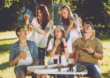 Pizza yemek Park piknik üzerinde neşeli arkadaşlar.