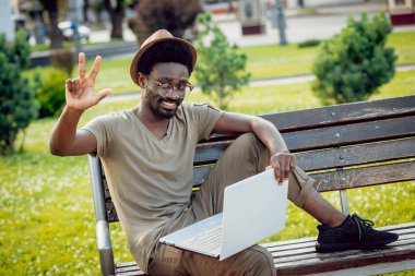 Afrika delikanlı şapka ve gözlük yeşil Şehir Parkı içinde laptop ile