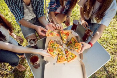 Pizza yemek Park piknik üzerinde neşeli arkadaşlar.
