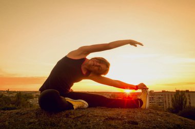 Genç kızı pratik Yoga çatıda. Gün batımında siluet.