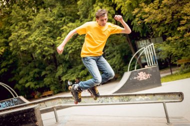 Young roller doing tricks in skatepark clipart