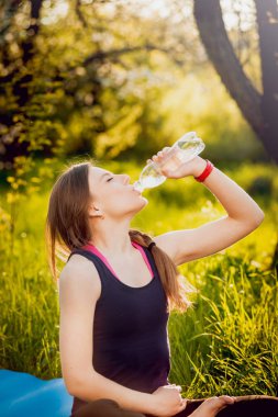 Genç kızı pratik Yoga park ve içme suyu