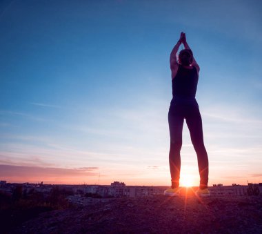 Gün batımında pratik Yoga çatıda genç kız.