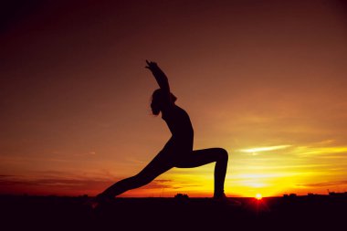 Genç kız yoga çatıda. Siluet