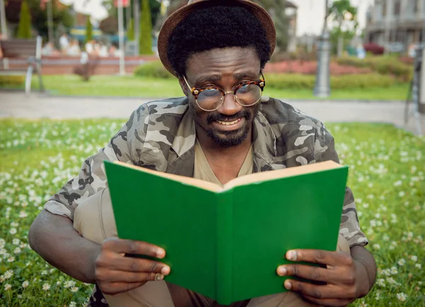 Young african man reading book in city park