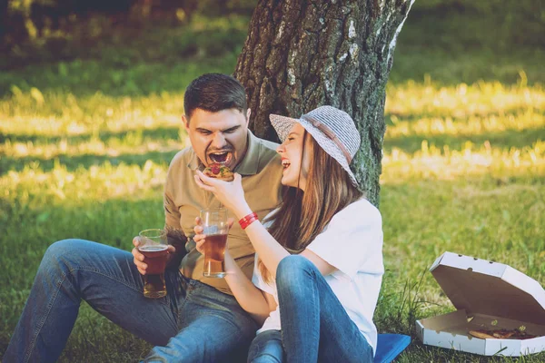 Mutlu çift pizza yiyip bira içmeyi Park piknik üzerinde.