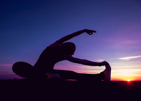 Young girl yoga on the roof. Silhouette