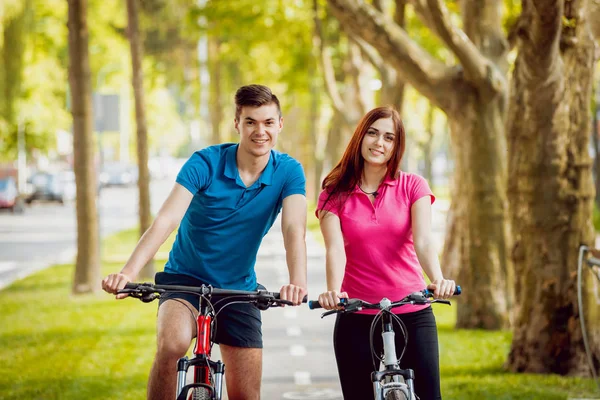 Genç çift yeşil Bisiklet lane güneşli bir günde Bisiklete binme
