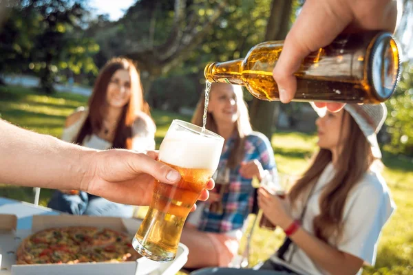 Parkta piknik neşeli Beyaz arkadaşlar. Gülümseyen ve konuşurken, enjoing pizza bira ile.