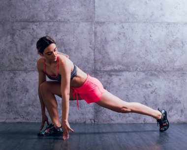 Studio poz ve farklı egzersizleri yapıyor genç atletik beyaz kadın.